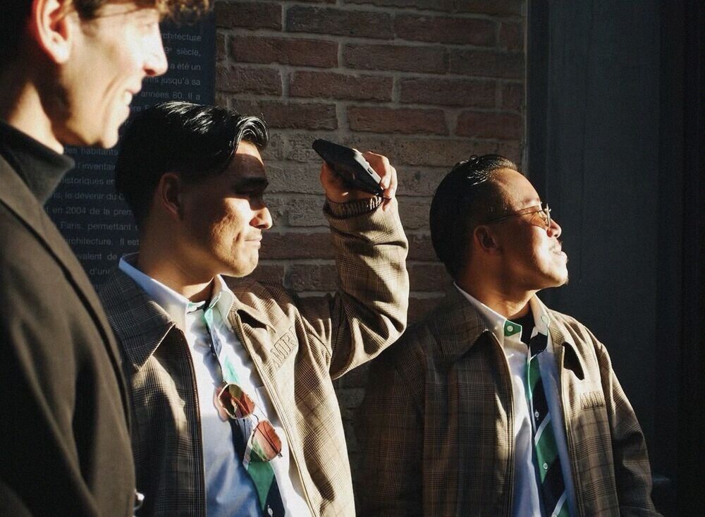 Three men in coats looking up in the sun