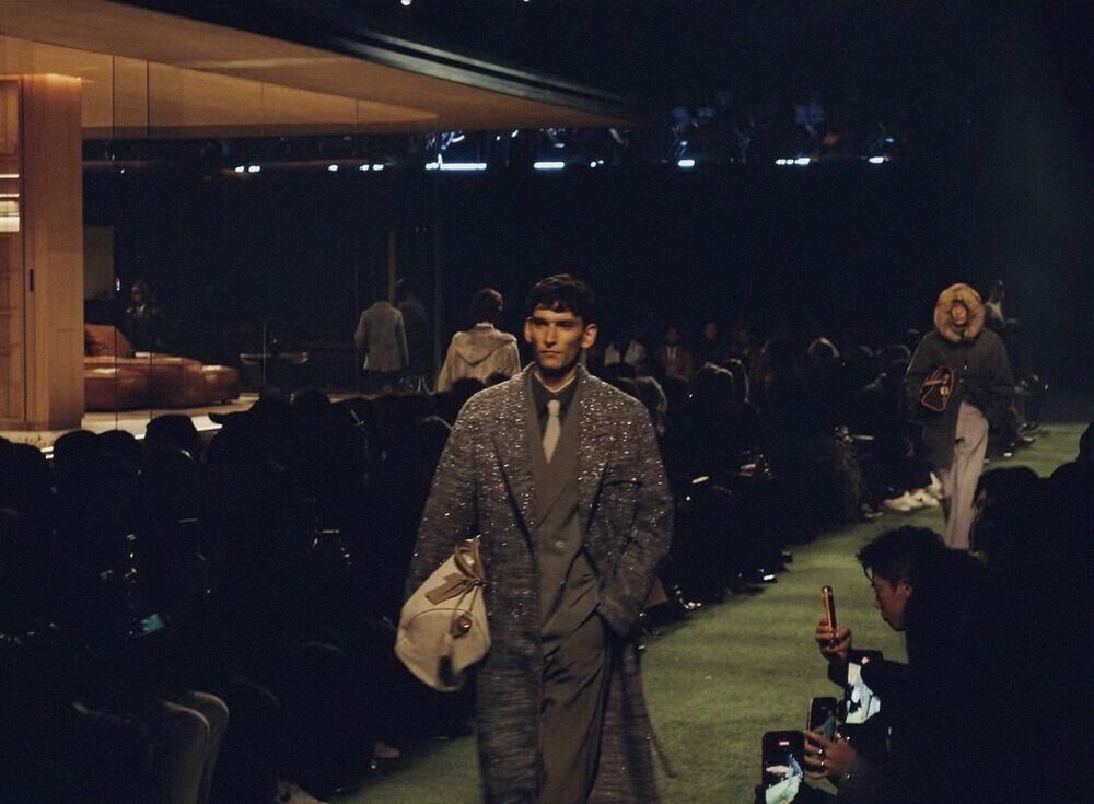 Model walks a long runway lined with seated guests