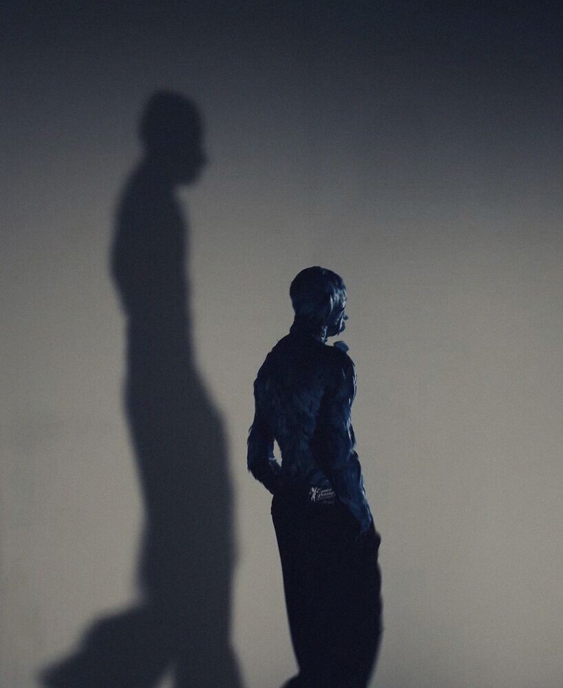 A figure and its long shadow on a pale wall