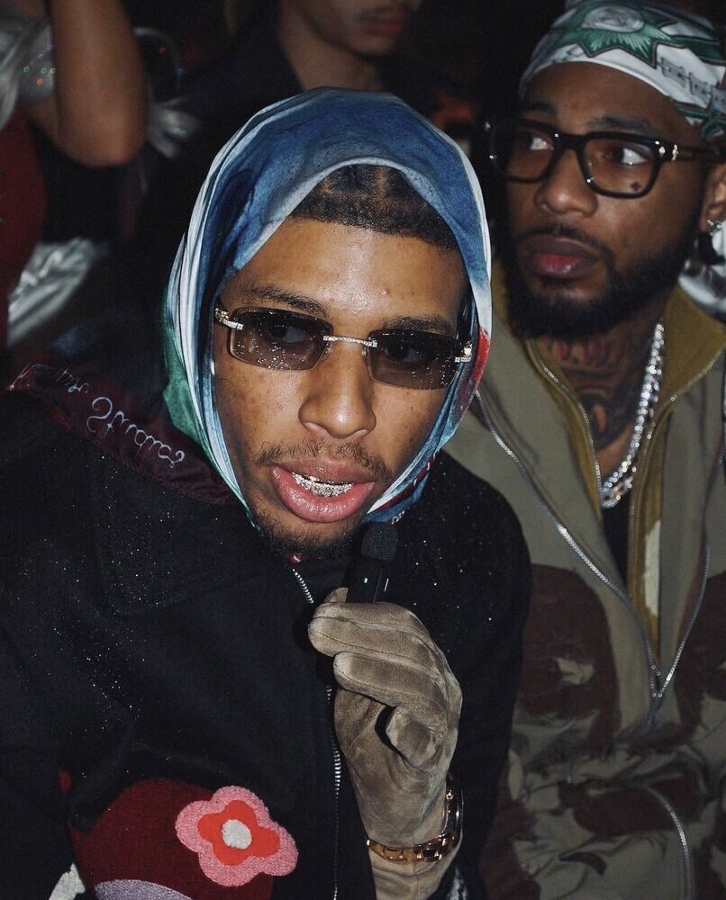 Man in a headscarf and sunglasses holding a microphone