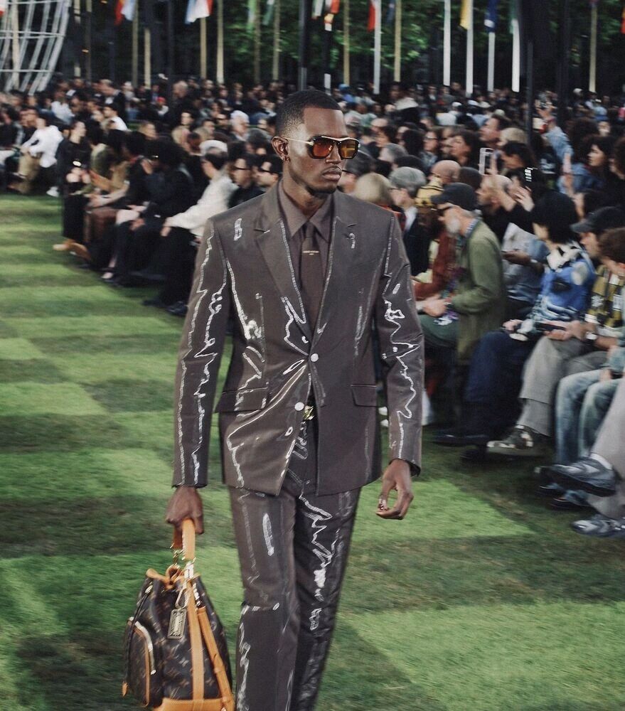 Model in a glossy suit on a grass runway
