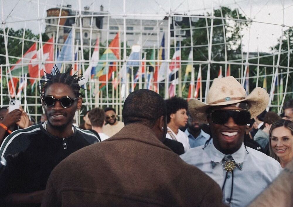 Crowd under rows of flags, one guest in a cowboy hat